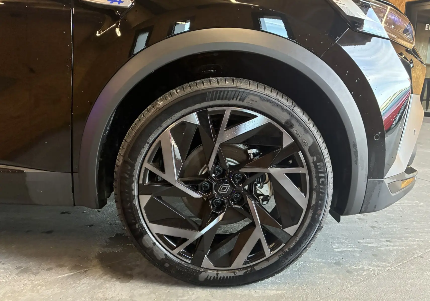 Gros plan sur la roue avant droite du Renault Captur noir étoile avec jante diamantée et badge Esprit Alpine bleu.