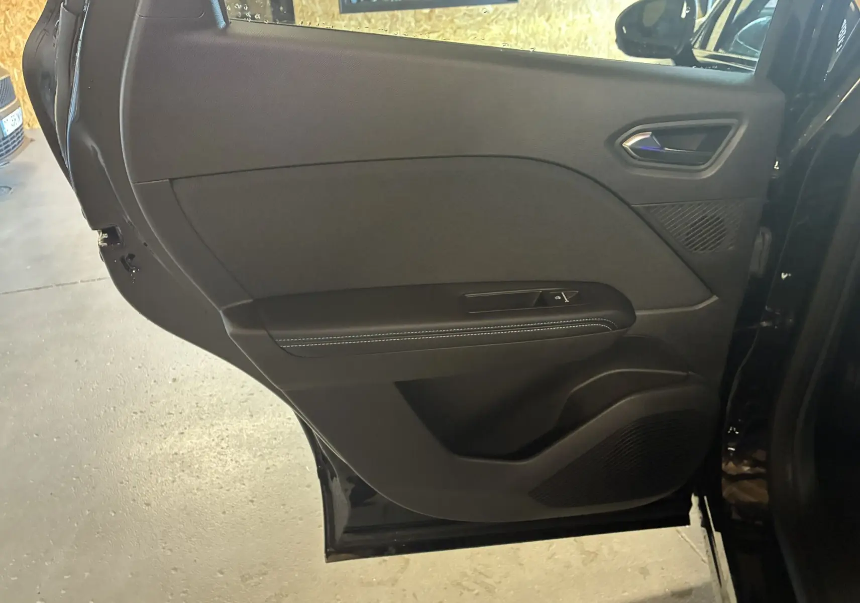 Vue intérieure du panneau de porte arrière droite noir étoile métal du Renault Captur E-Tech Full Hybrid 2025 avec surpiqûres blanches.