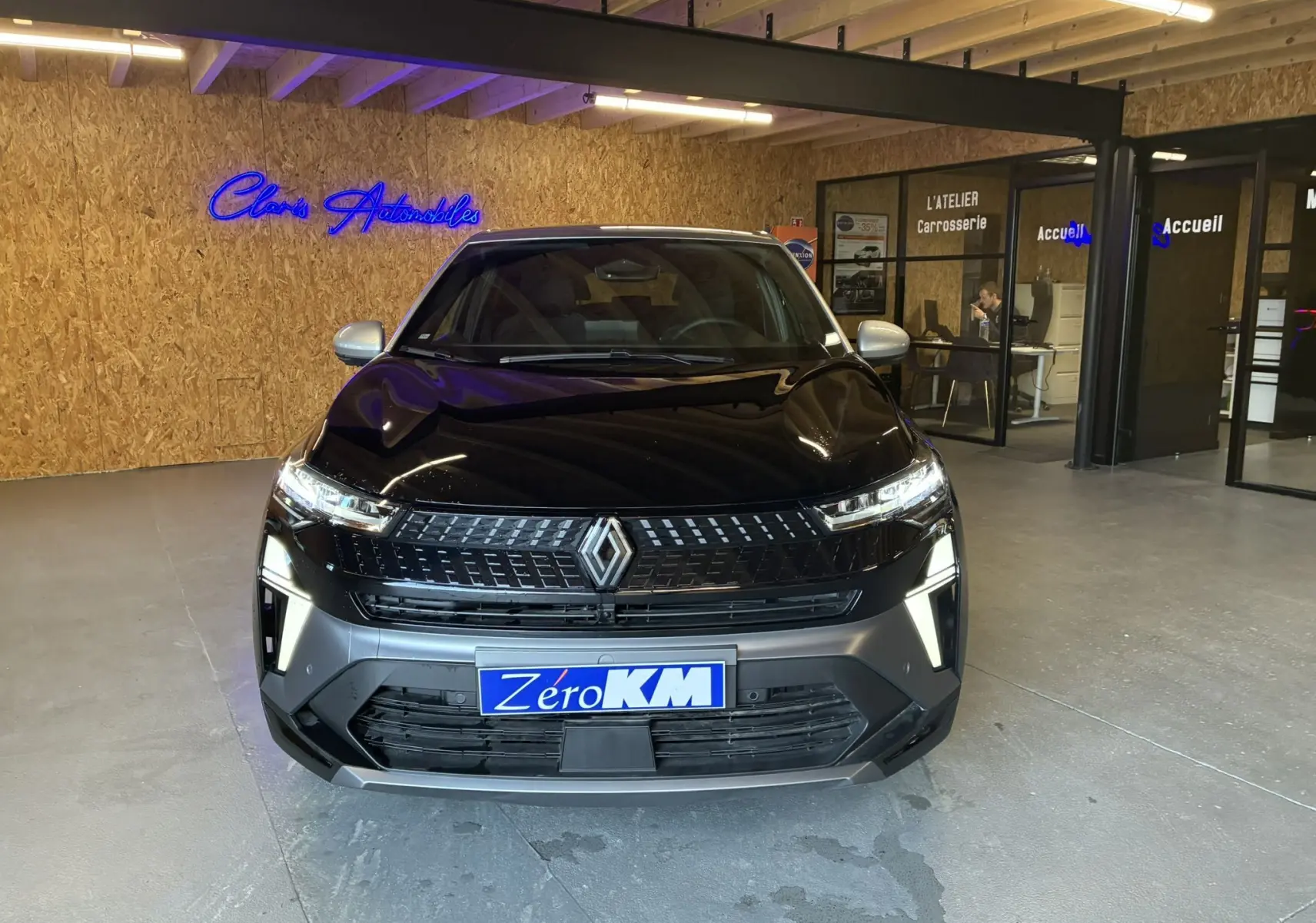 Renault Captur E-Tech hybride 2025 noir étoile avec toit gris, vue frontale dans un showroom moderne.