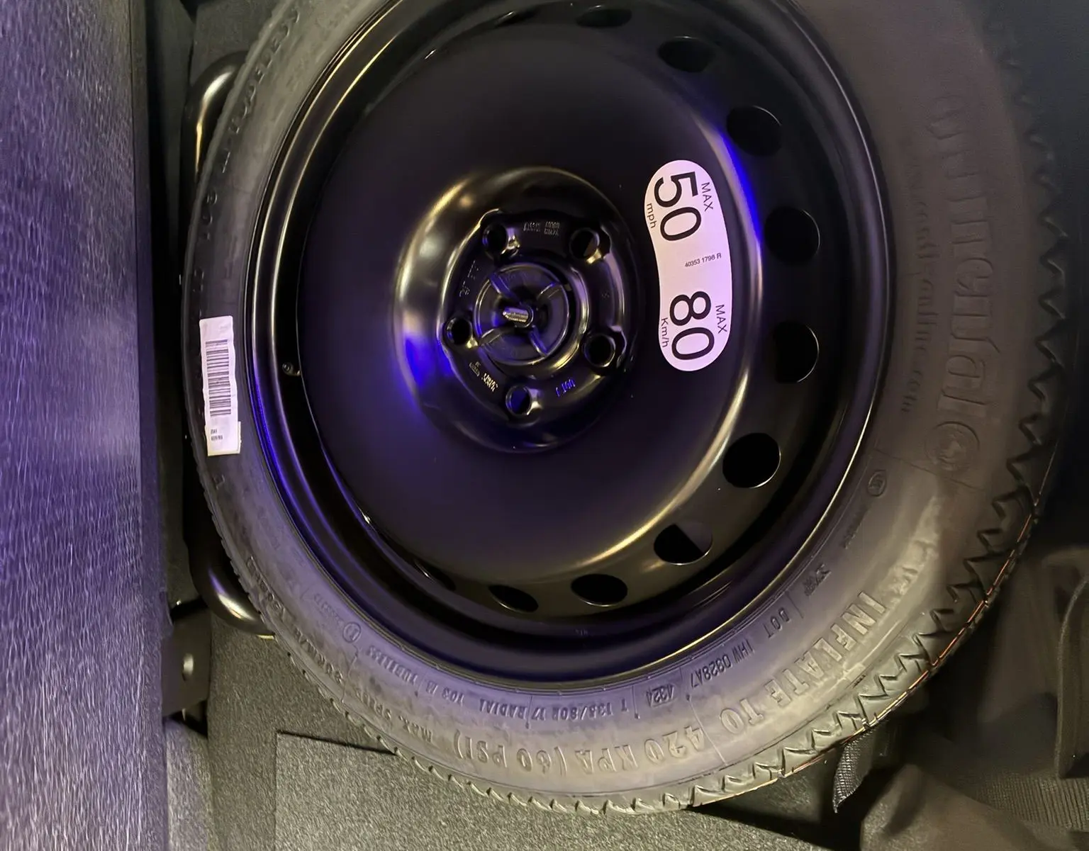 Roue de secours noire avec étiquette de vitesse 50 mph/80 km/h, logée dans le coffre d'un Renault Captur 2025 hybride.