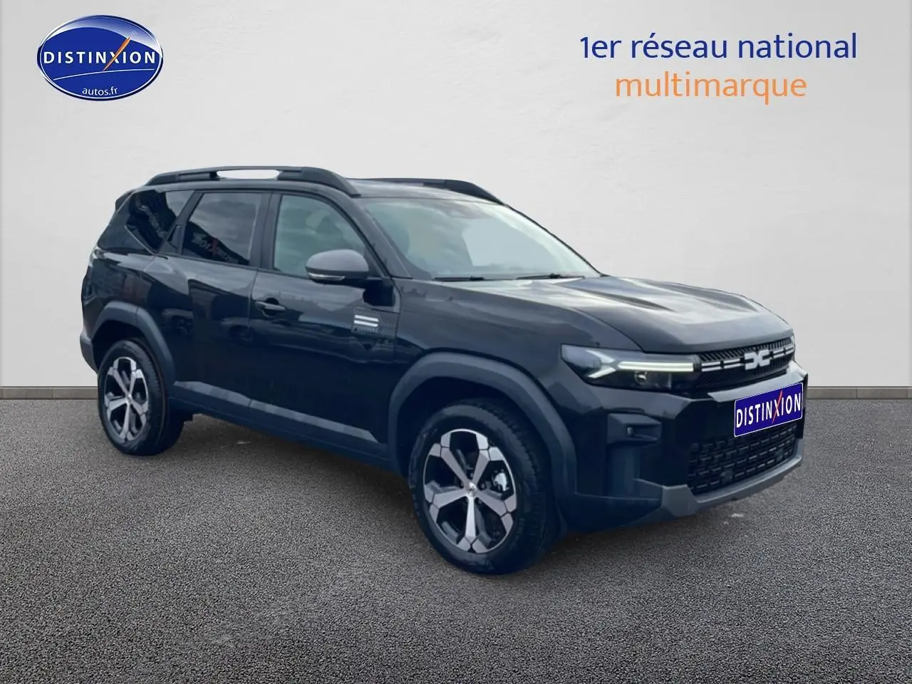 SUV Dacia Bigster noir en 3/4 avant droit, avec jantes alliage diamantées et barres de toit visibles.