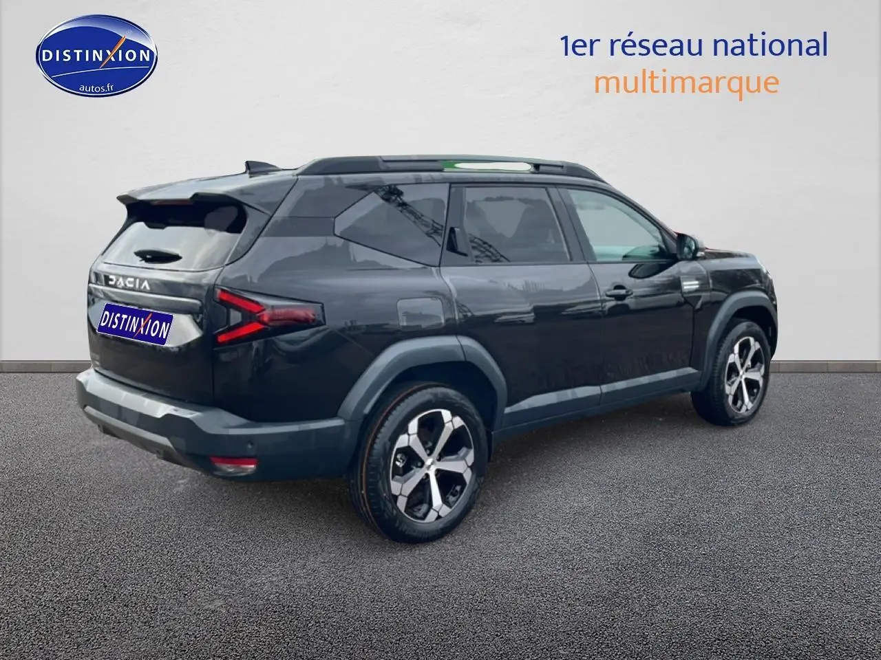 Vue 3/4 arrière droite du SUV Dacia Bigster noir avec jantes alliage diamantées et barres de toit visibles.