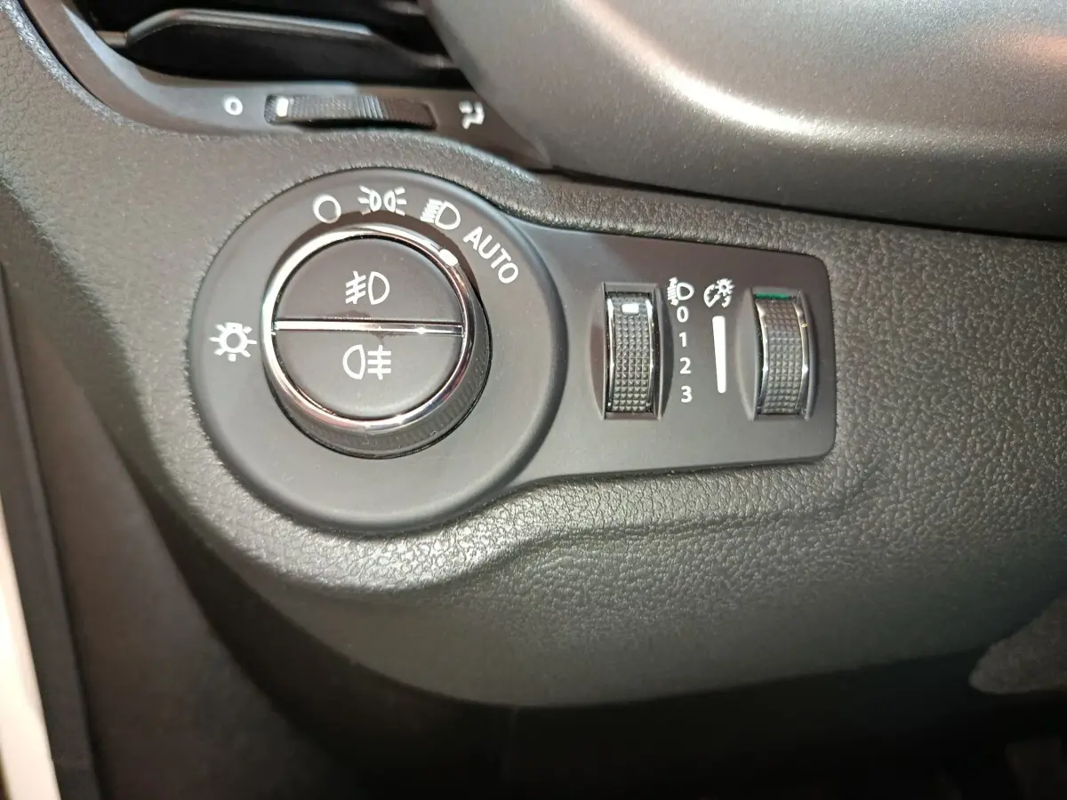 Gros plan sur la commande des phares et réglages d’éclairage à gauche du tableau de bord d’une Fiat 500X noire.
