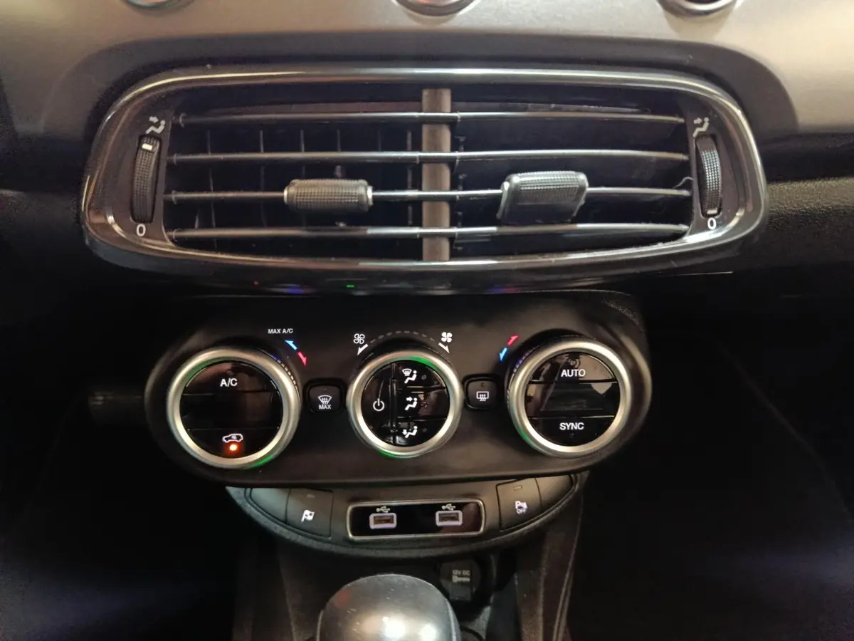 Vue rapprochée du tableau de bord noir de la Fiat 500X 2021, montrant les commandes de climatisation et les aérateurs.