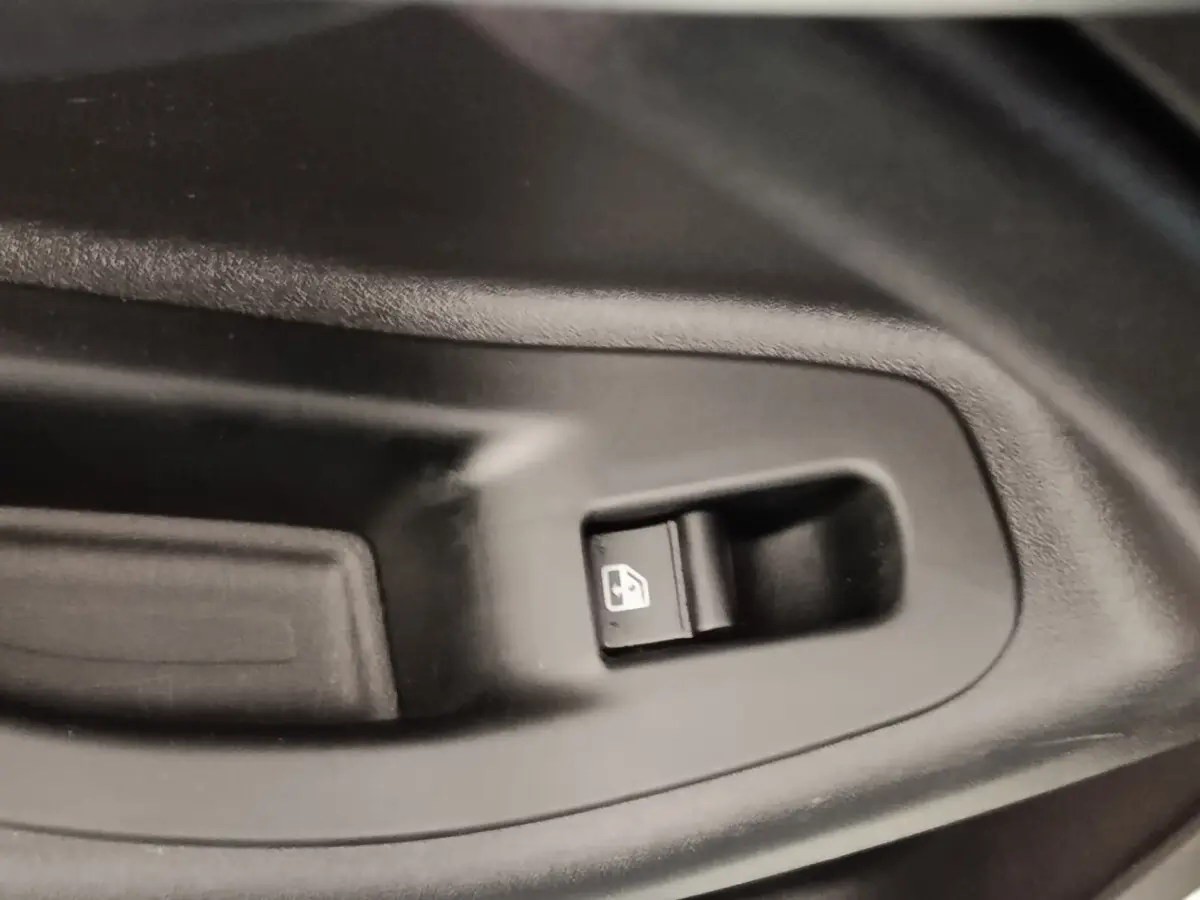 Gros plan sur le bouton de commande de lève-vitre électrique côté conducteur d'une FIAT 500X noire.