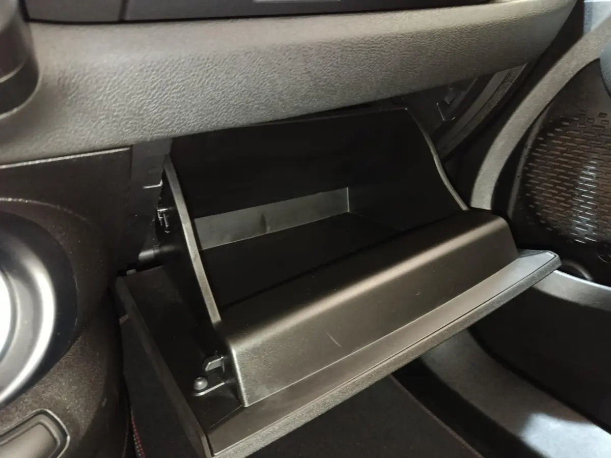 Vue rapprochée de la boîte à gants noire ouverte côté passager dans l’habitacle d’une Fiat 500X noire.