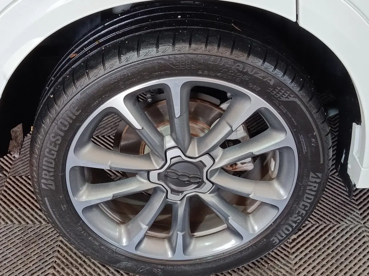 Gros plan sur la jante alliage grise et le pneu Bridgestone d'une FIAT 500X noire, vue côté droit arrière.
