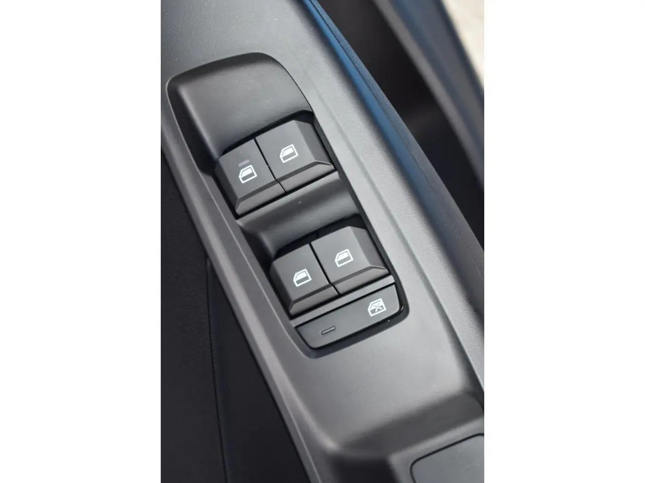 Gros plan sur les commandes de lève-vitres côté conducteur du MG3 1.5 HYBRID+ 195 LUXURY 2026, intérieur noir.