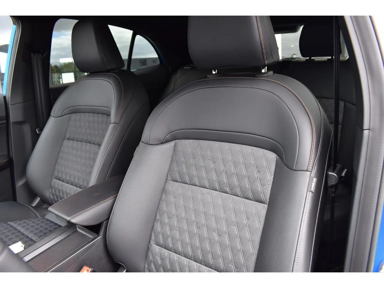 Gros plan sur les sièges avant en cuir noir avec surpiqûres orange du MG3 1.5 HYBRID+ 195 Luxury bleu, vue intérieure côté droit.