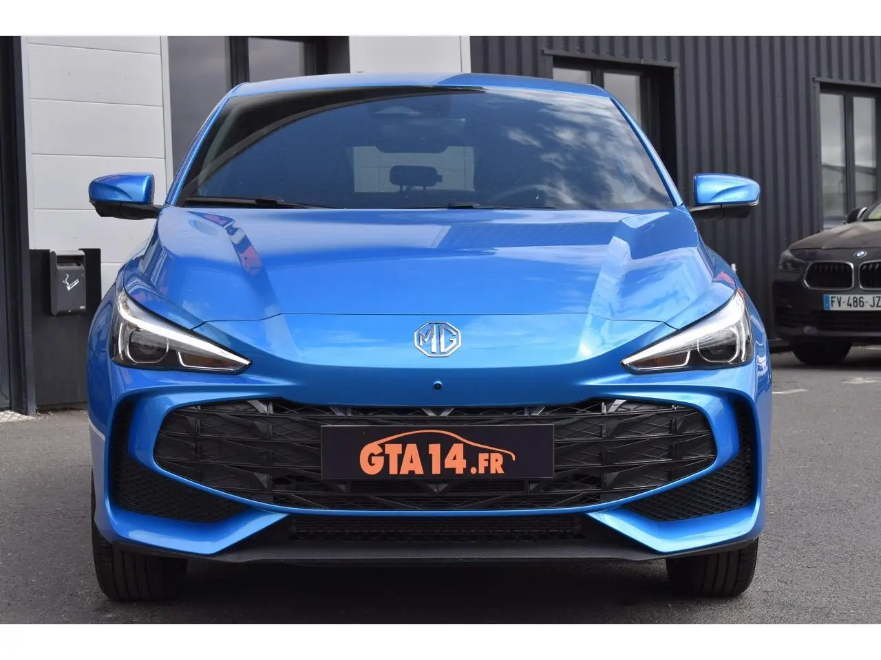 Vue frontale d'une MG3 1.5 HYBRID+ 195 LUXURY bleue métallisée avec calandre noire et phares LED marqués.