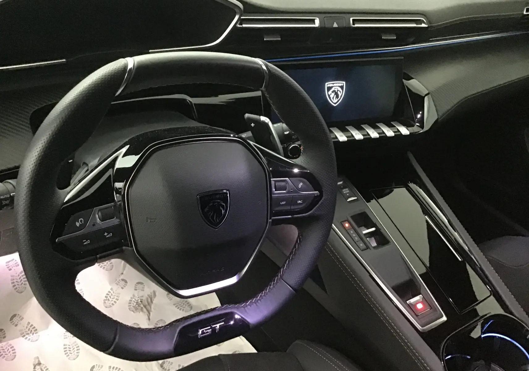 Vue intérieure centrée sur le volant GT et la console centrale noire brillante du Peugeot 508 SW 2024.