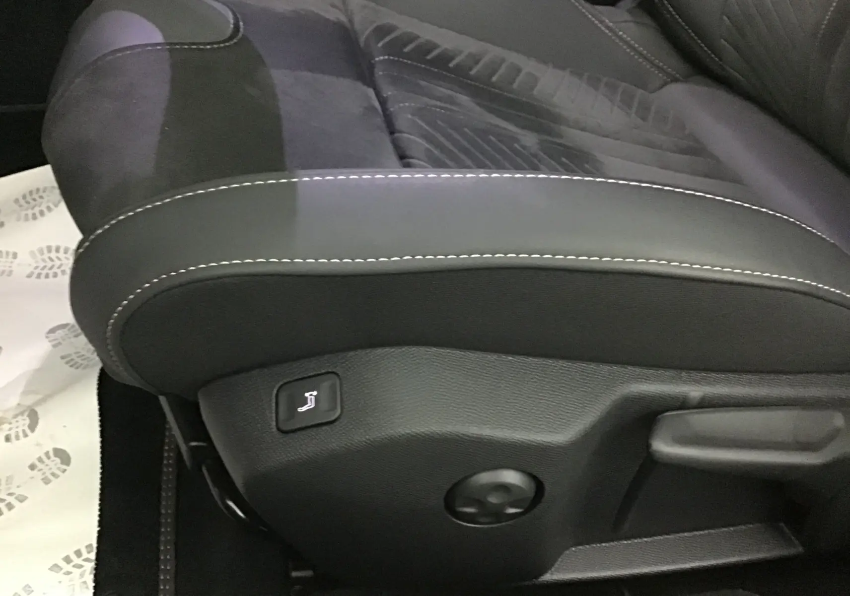 Détail du siège avant gauche en tissu et cuir noir avec surpiqûres blanches dans une Peugeot 508 SW gris Artense.