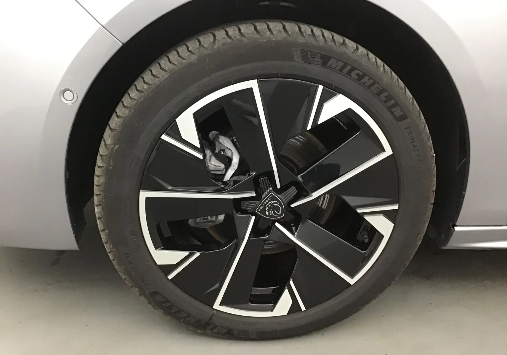 Gros plan sur la roue avant gauche d'une Peugeot 508 SW gris Artense avec jante noire et argentée au design moderne.