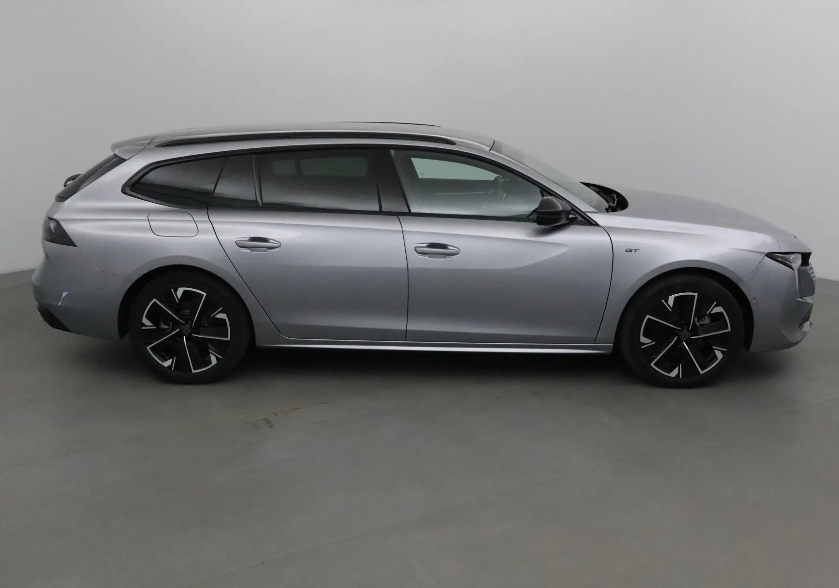 Profil côté droit de la Peugeot 508 SW gris Artense 2024, finition GT avec jantes noires et toit panoramique.
