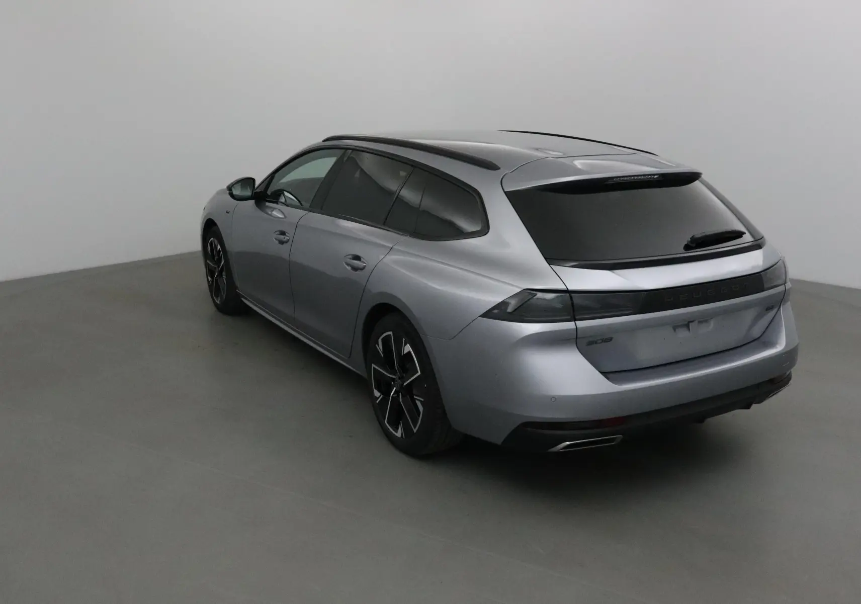 Peugeot 508 SW gris Artense vue 3/4 arrière droit, avec vitres teintées et jantes noires distinctives.