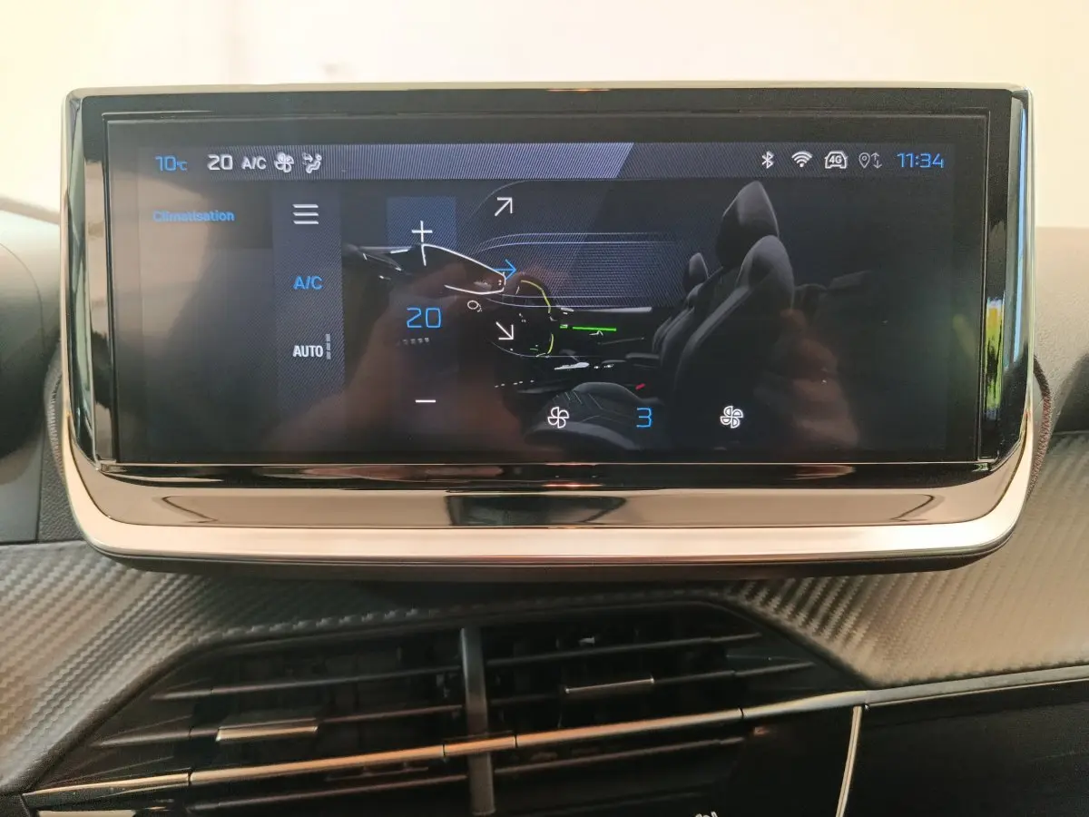 Écran tactile central affichant la climatisation dans l’habitacle d’une Peugeot 208 gris foncé, vue de face.