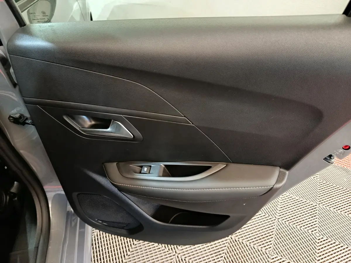 Vue intérieure côté gauche de la porte arrière grise foncée du Peugeot 208 PureTech 100 S&S Allure 2025.