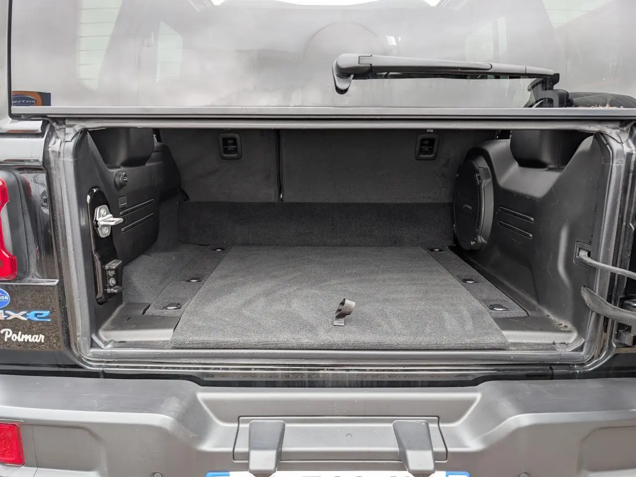 Coffre ouvert d’un Jeep Wrangler 2024 noir, montrant l’espace de rangement intérieur et la roue de secours souple.