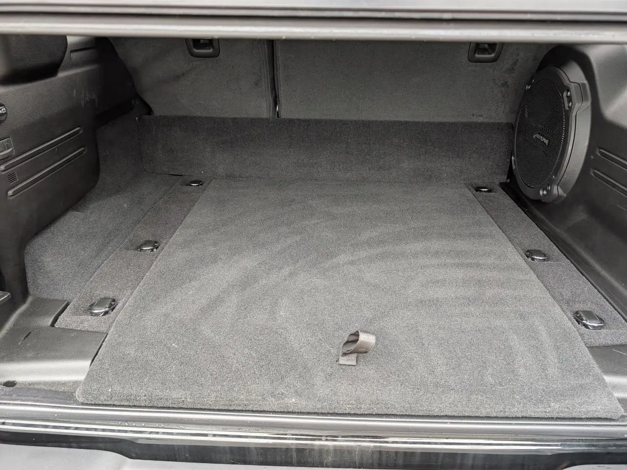 Vue intérieure du coffre noir du Jeep Wrangler 2024 Unlimited Sahara avec caisson de basse Alpine intégré à droite.