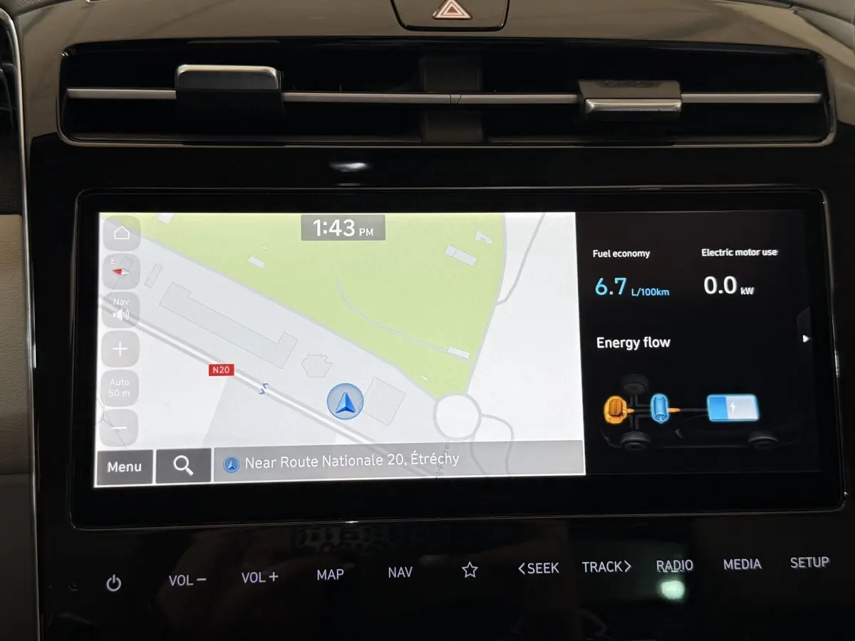 Écran tactile central du Hyundai Tucson gris foncé 2021 affichant navigation 3D et consommation hybride.