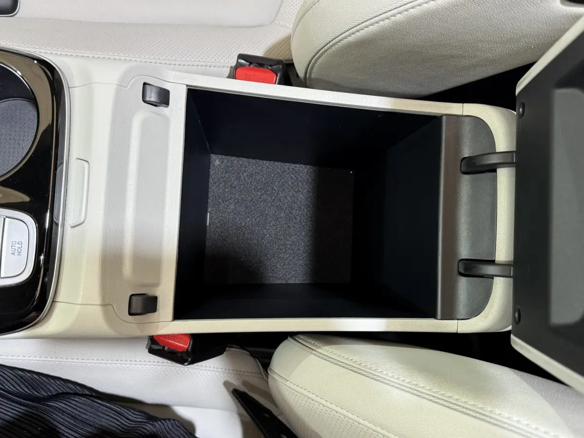 Vue plongeante sur le rangement central ouvert avec intérieur noir et sellerie cuir beige du Hyundai Tucson 1.6 Hybrid 230 Executive.