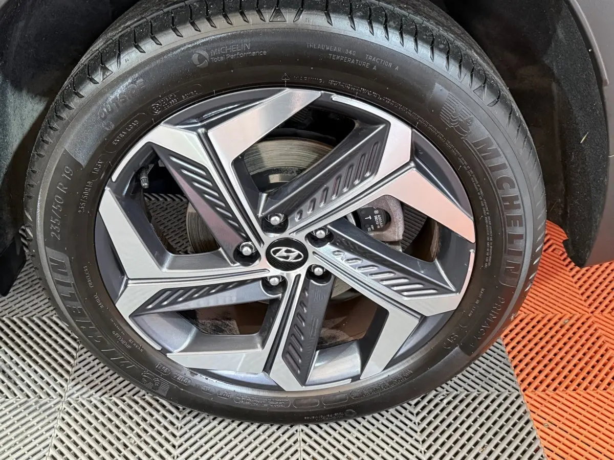 Gros plan sur la jante alliage bicolore et pneu Michelin du côté droit d’un Hyundai Tucson gris foncé.