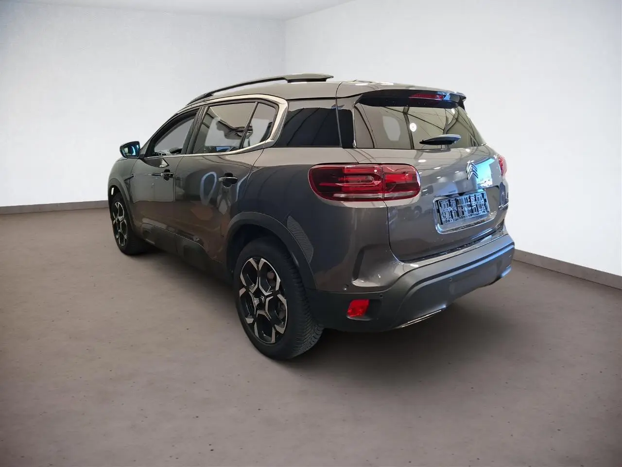 Vue 3/4 arrière droit d'un Citroën C5 Aircross gris Platinium avec jantes alliage et vitres teintées.