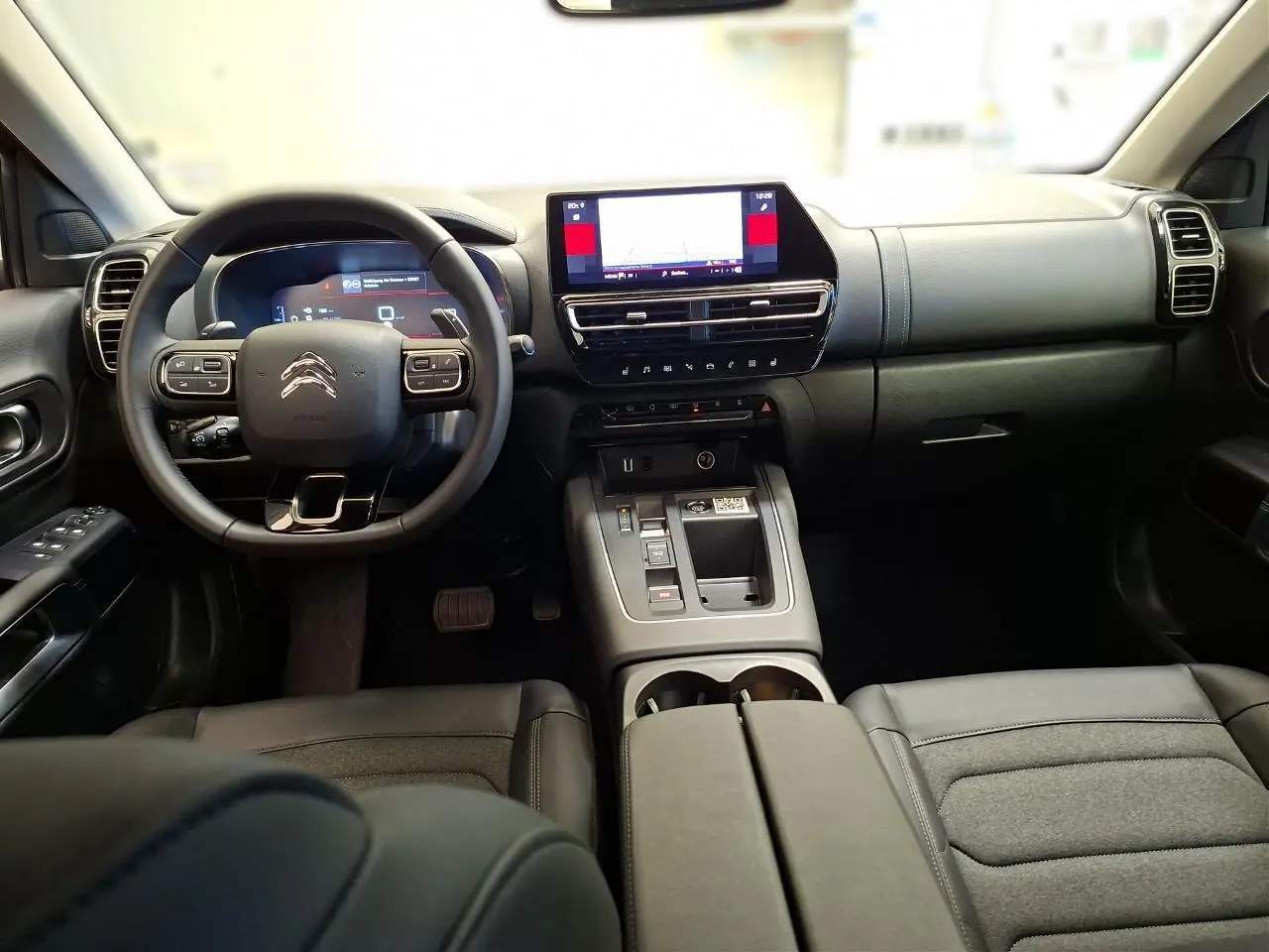 Vue intérieure avant du Citroën C5 Aircross 2025, tableau de bord et volant noir avec écran tactile central lumineux.
