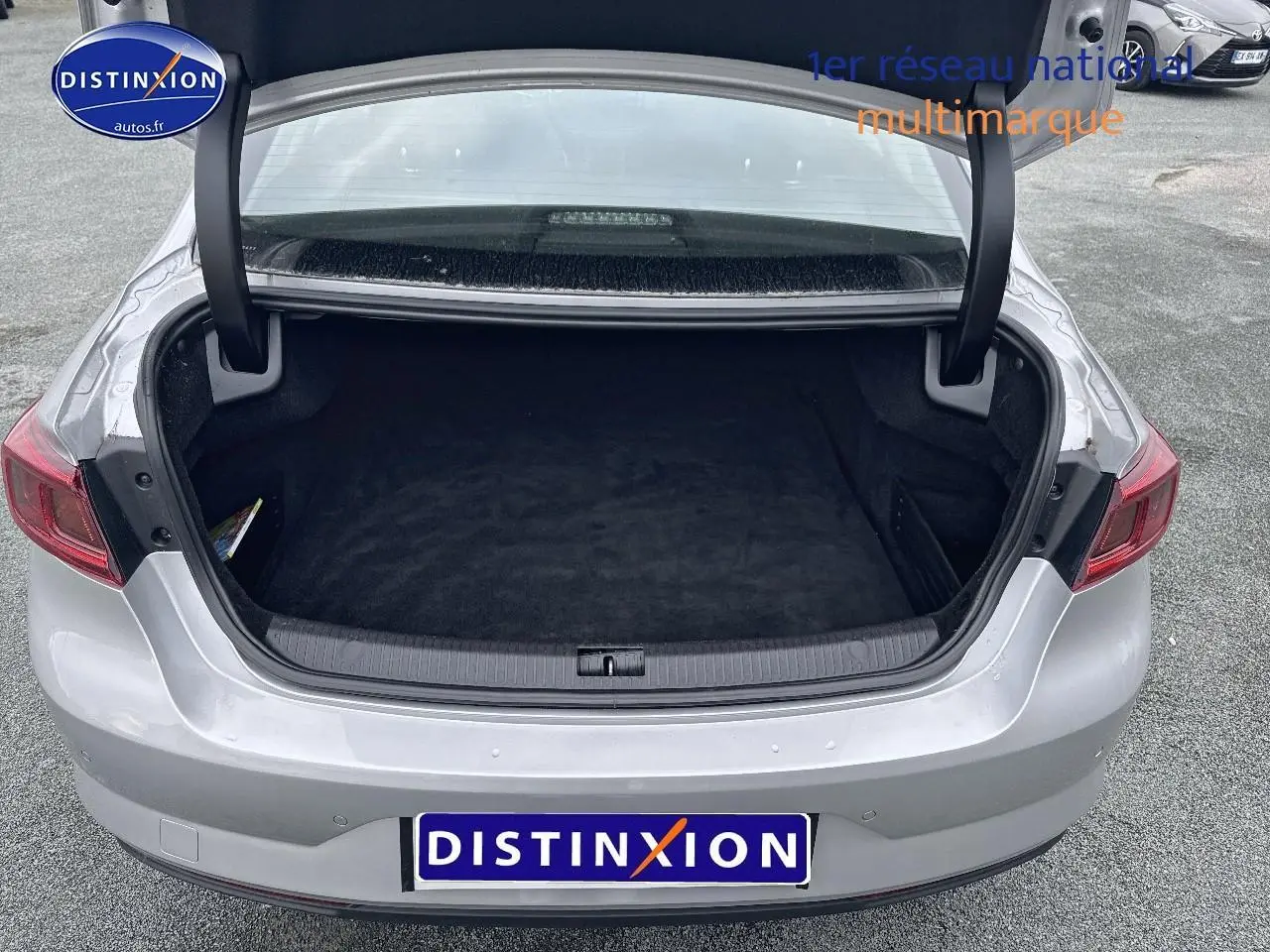 Coffre ouvert vu de l'arrière d'une Renault Talisman gris alu 2020 avec feux arrière rouges et parking en arrière-plan.