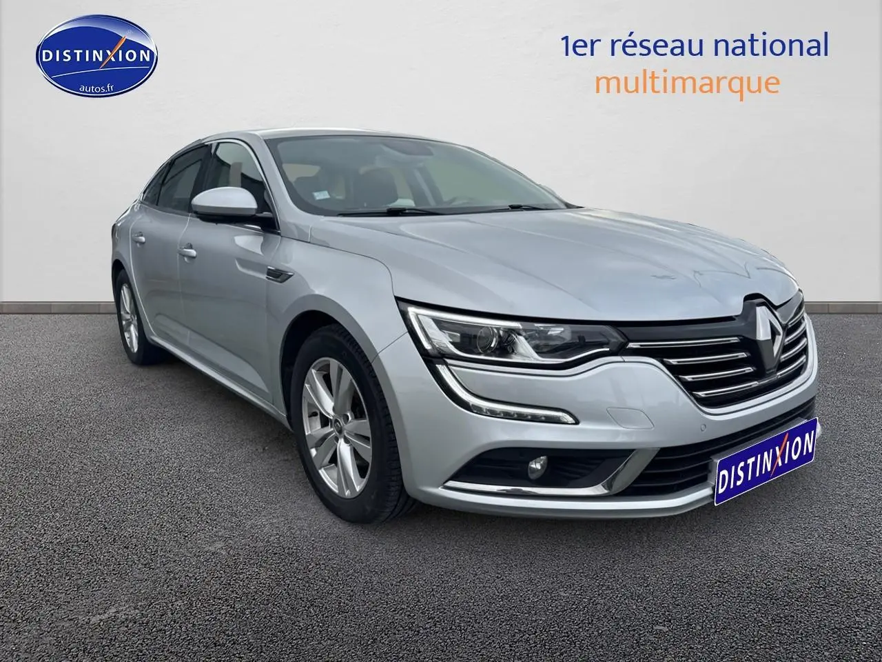 Renault Talisman gris alu en 3/4 avant droit, avec calandre distinctive et jantes alu visibles.