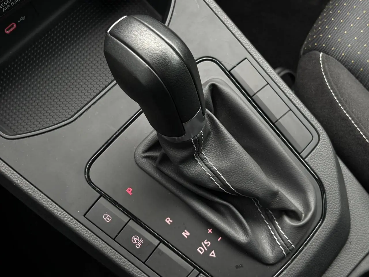 Gros plan sur le levier de vitesses automatique noir avec coutures blanches dans l’habitacle d’une SEAT Ibiza argent urbain.