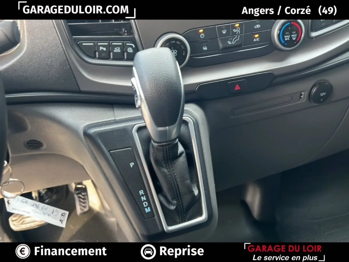Gros plan sur le levier de vitesses automatique et la console centrale du Ford Transit Custom blanc, intérieur noir.