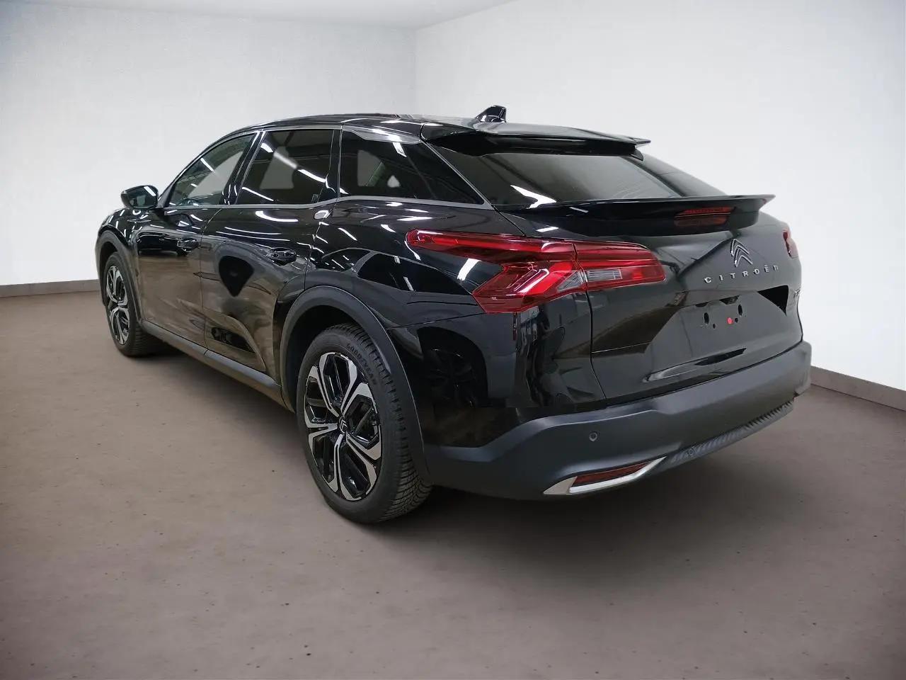 Vue rapprochée du volant cuir noir du Citroën C5 X 2024 avec commandes intégrées et tableau de bord numérique.