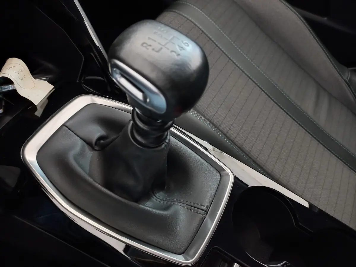 Gros plan sur le levier de vitesses manuel noir et la sellerie grise à motifs de la Peugeot 208 PureTech 100 S&S Allure.
