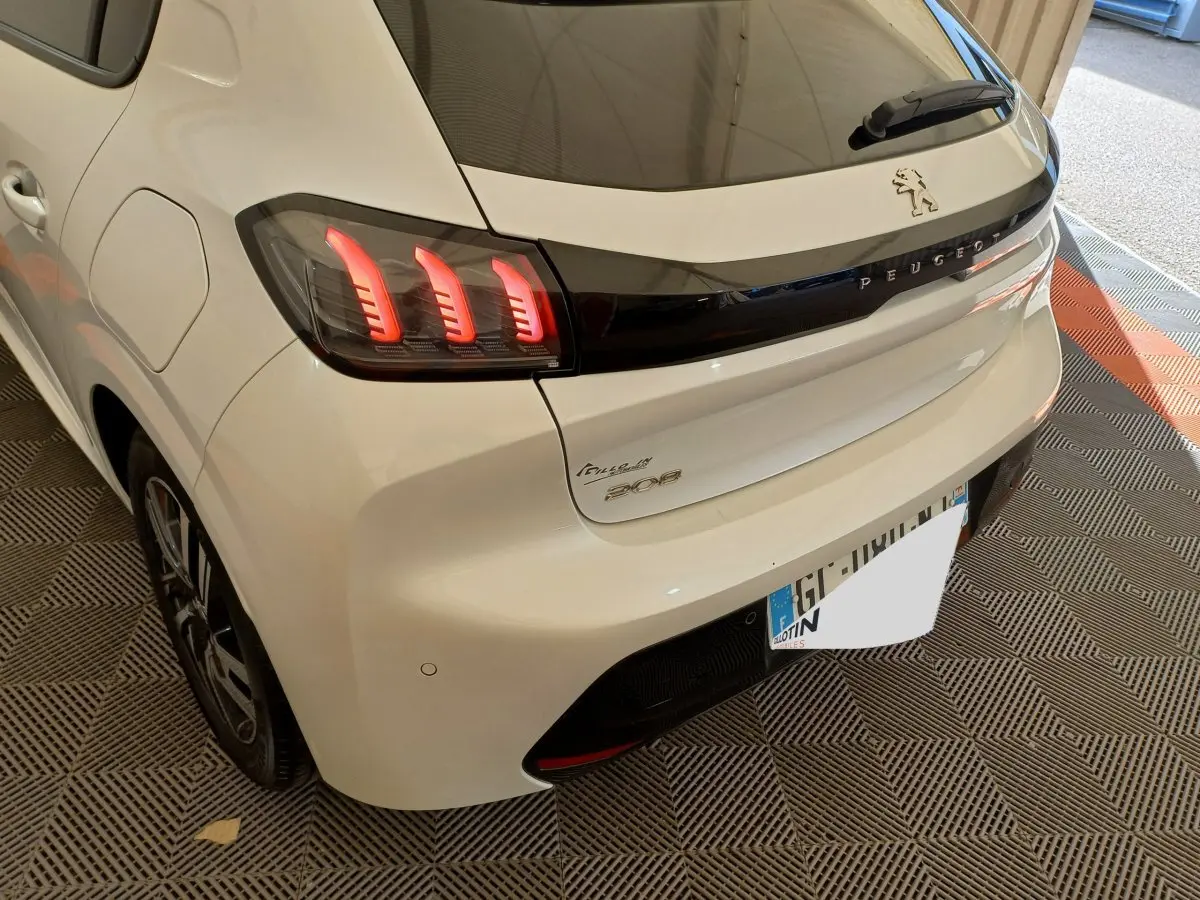 Vue 3/4 arrière droite d'une Peugeot 208 blanche avec feux arrière LED et logo Peugeot sur la malle.