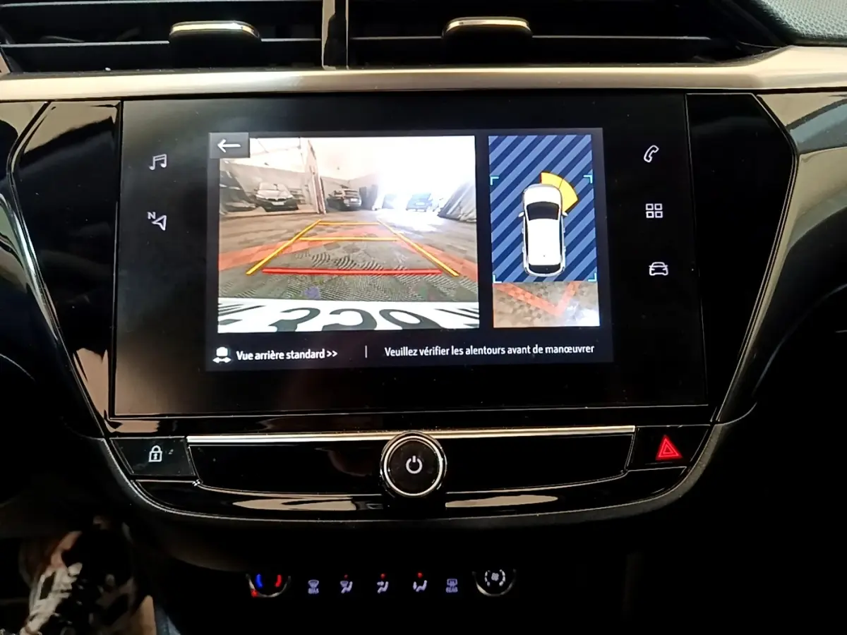 Écran tactile central de la console de l’Opel Corsa blanc 2023 montrant la caméra de recul et l’aide au stationnement.
