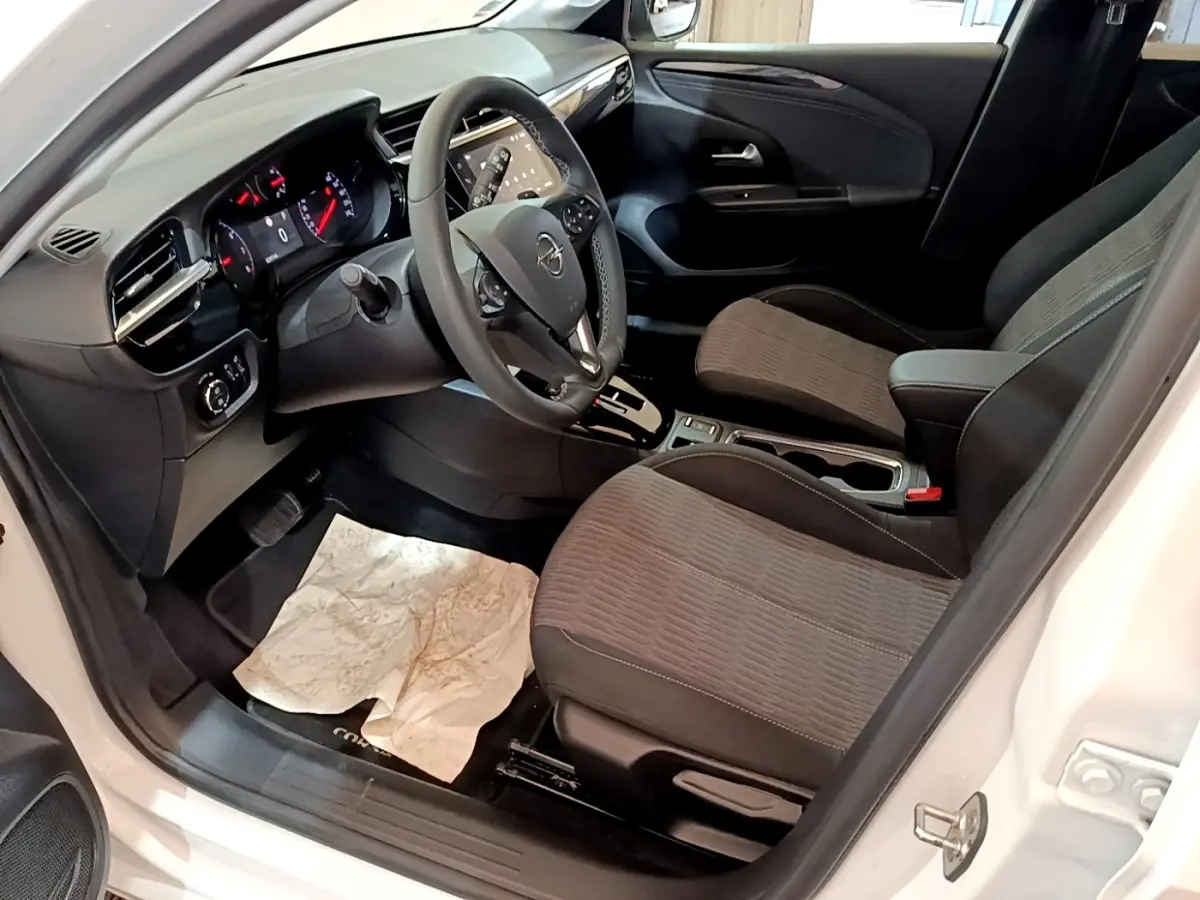 Vue intérieure côté conducteur de l’Opel Corsa blanc 2023, avec tableau de bord digital et sièges tissu gris.
