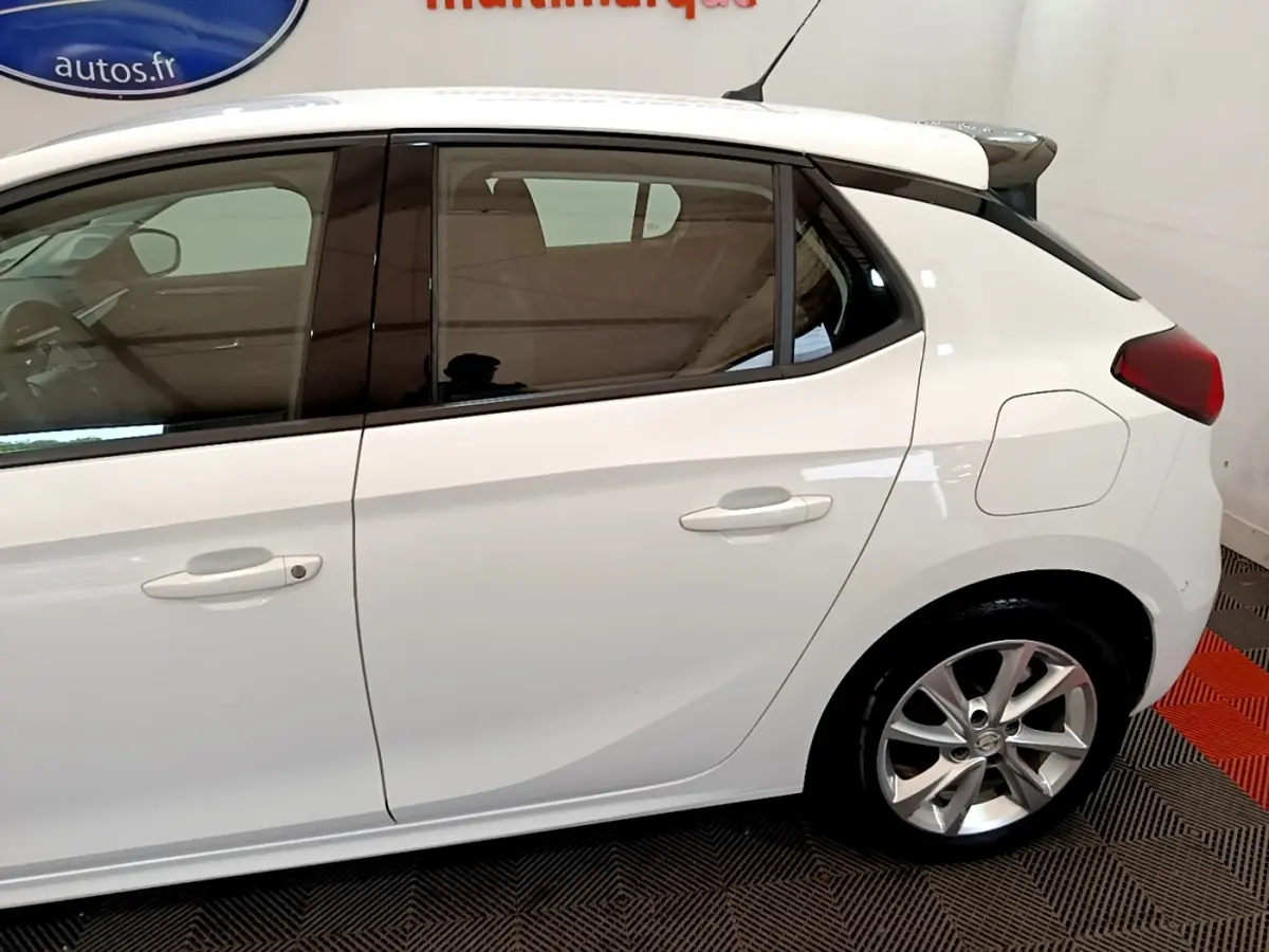Vue latérale côté droit d'une Opel Corsa blanche avec jantes alliage et spoiler de toit visible.