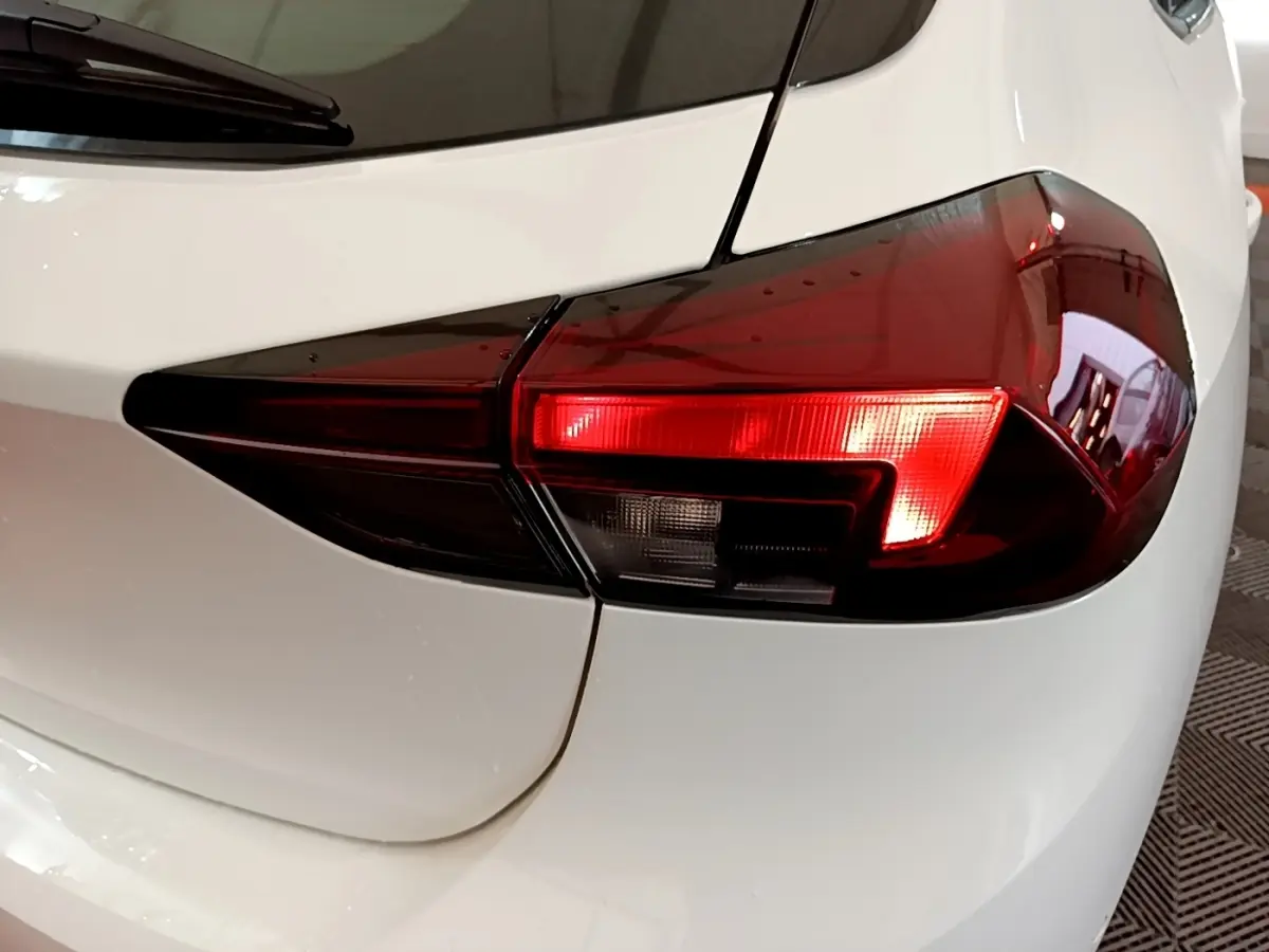 Gros plan sur le feu arrière droit rouge et noir de l’Opel Corsa blanche, vue arrière côté droit.