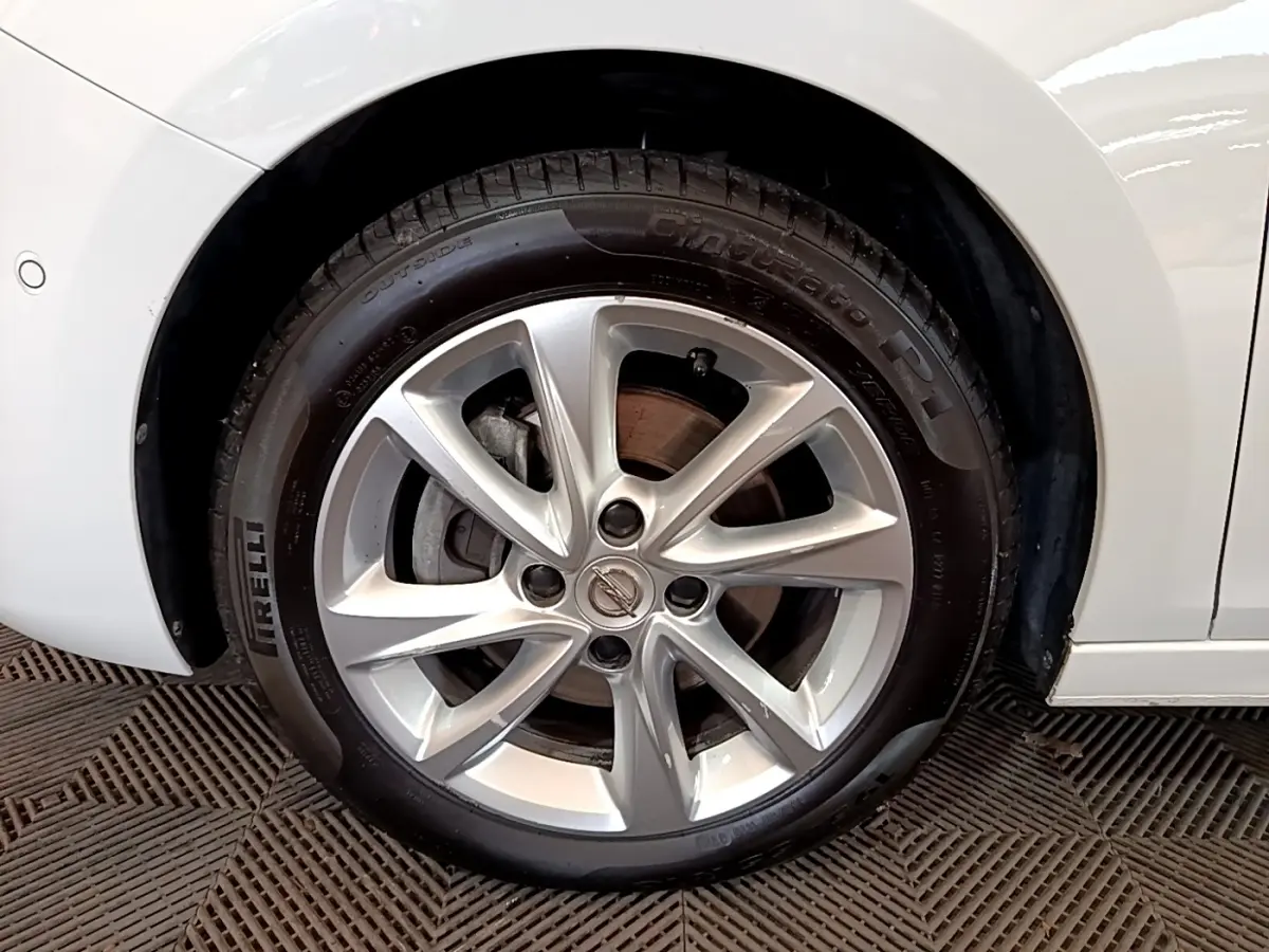 Gros plan sur la roue avant droite d’une Opel Corsa blanche, avec jante alliage argentée et pneu Pirelli.