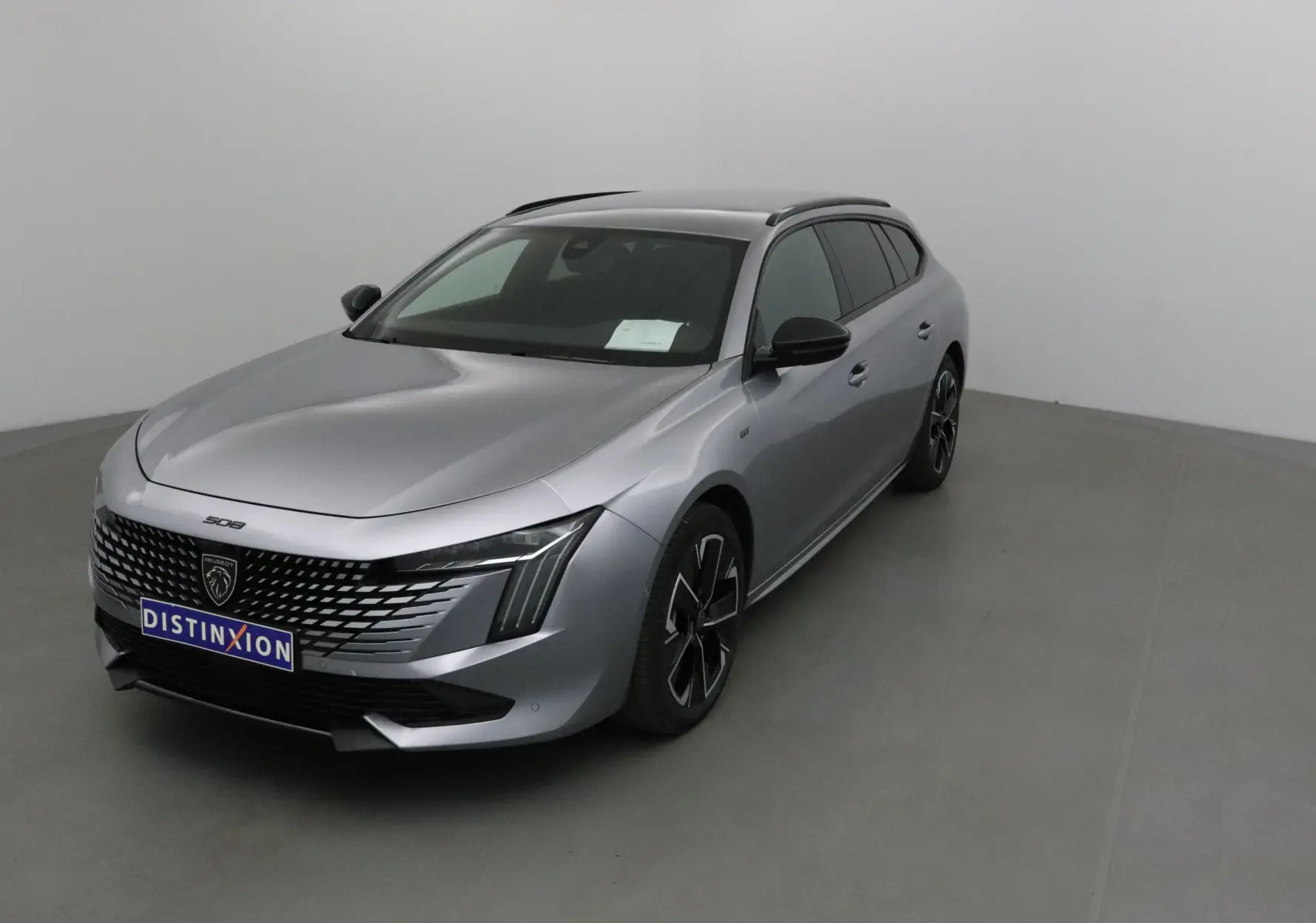 Peugeot 508 SW gris Artense vue 3/4 avant droit, avec calandre distinctive et phares Full LED modernes.