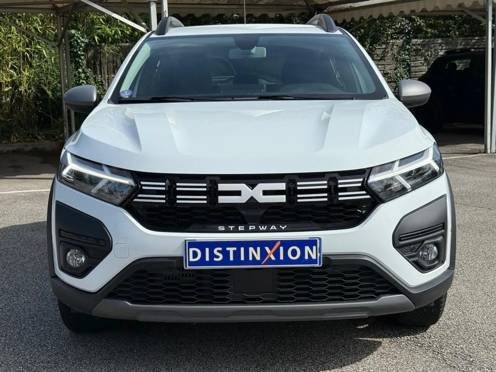 Vue frontale d'une Dacia Sandero Stepway blanche 2023 avec calandre noire et feux LED distinctifs.