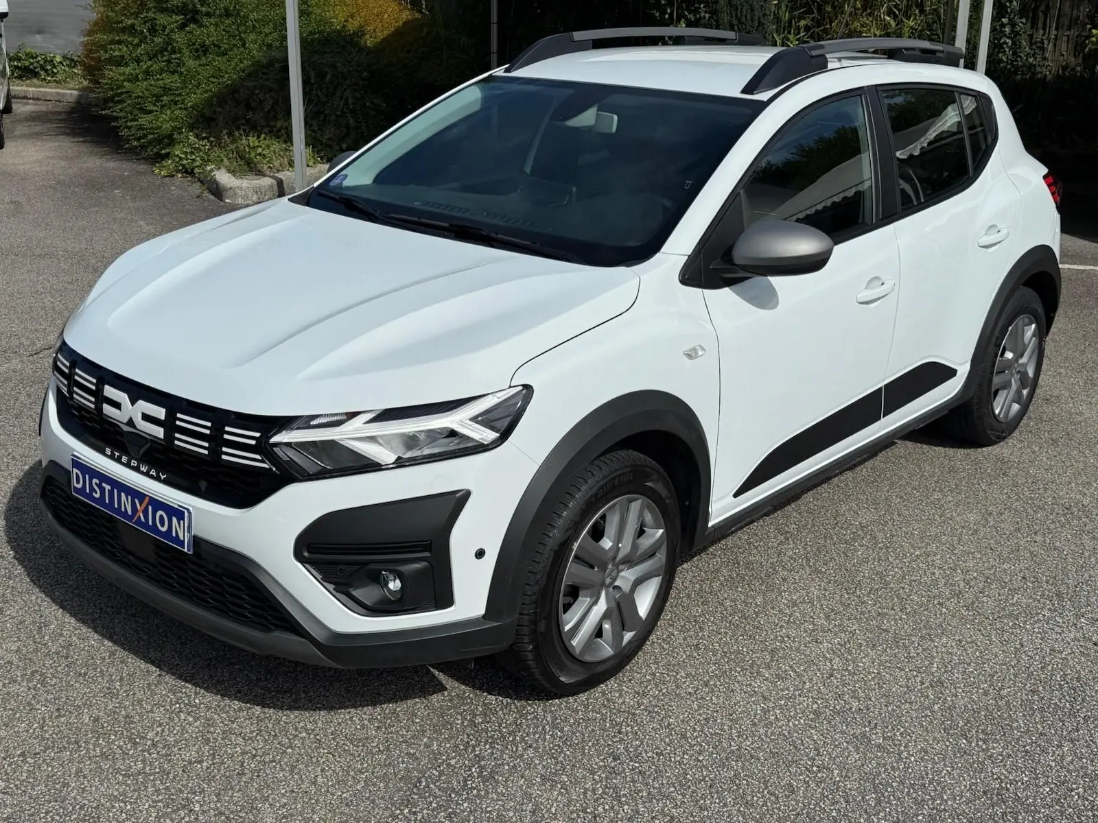 Vue 3/4 avant droite d'une Dacia Sandero Stepway blanche 2023 avec détails noirs et calandre distinctive.