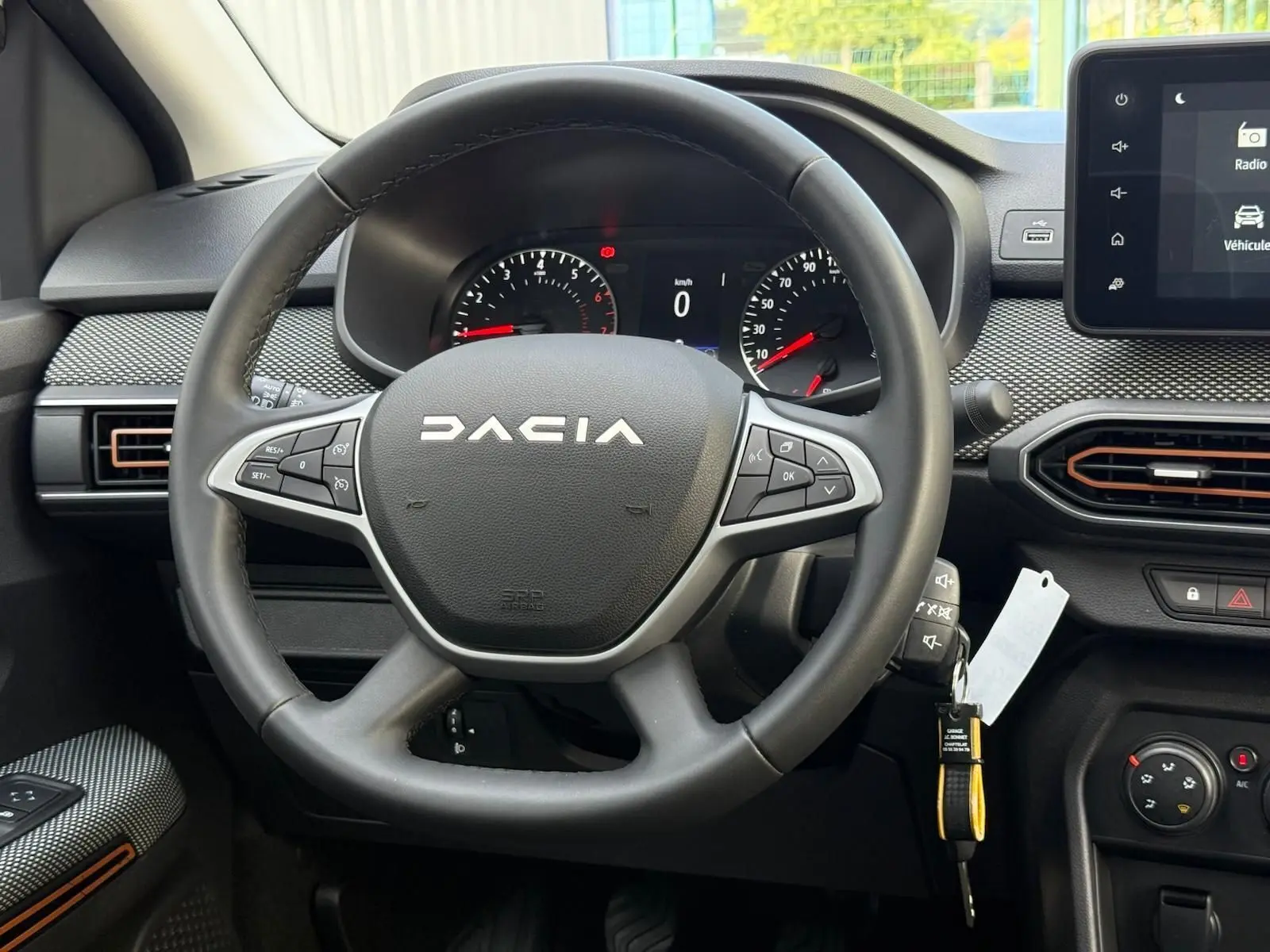 Vue rapprochée du volant noir de la Dacia Sandero 2023 avec tableau de bord et écran tactile visibles.