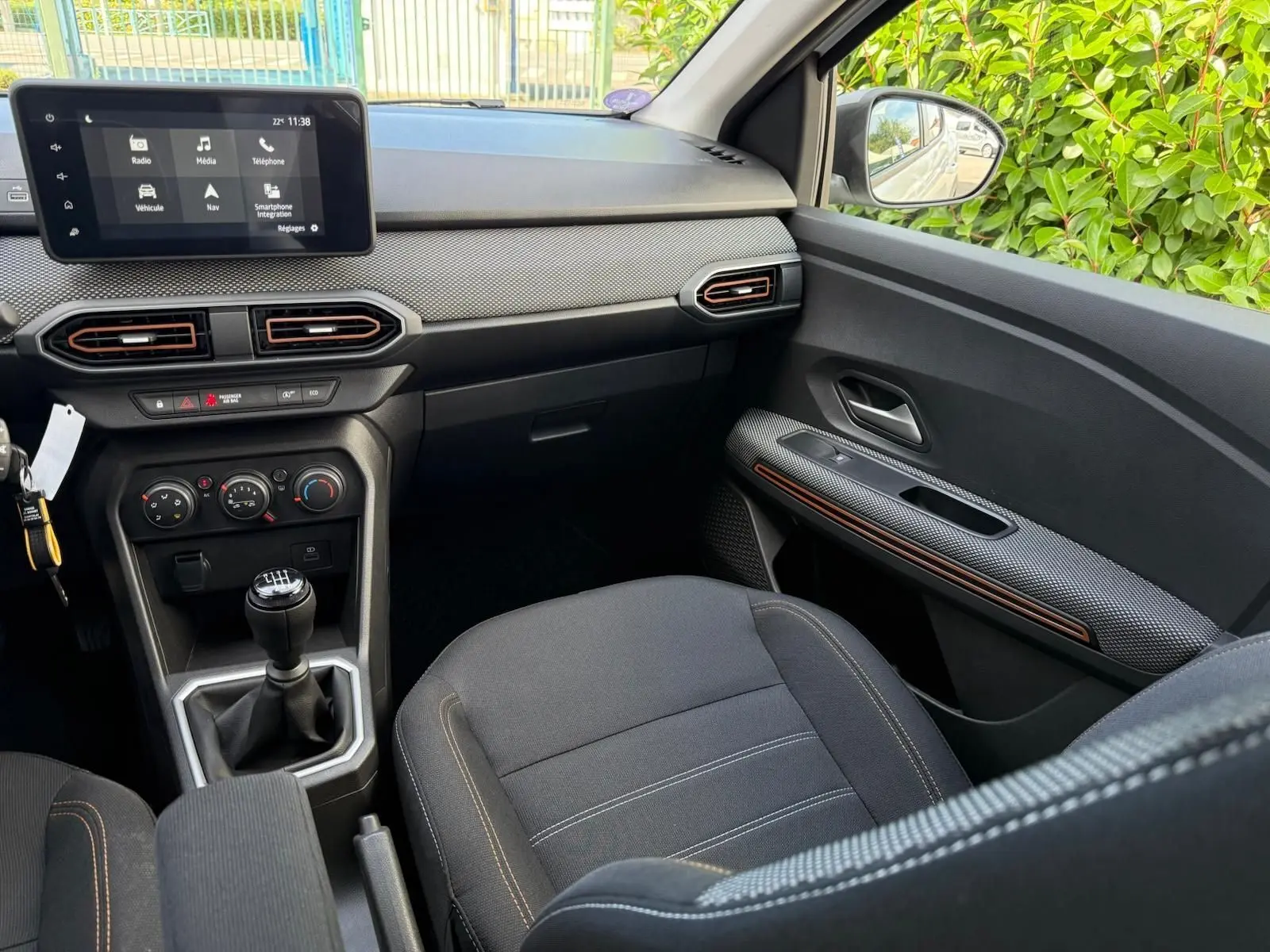 Vue intérieure côté passager de la Dacia Sandero Stepway blanche 2023, avec tableau de bord moderne et levier de vitesse manuel.