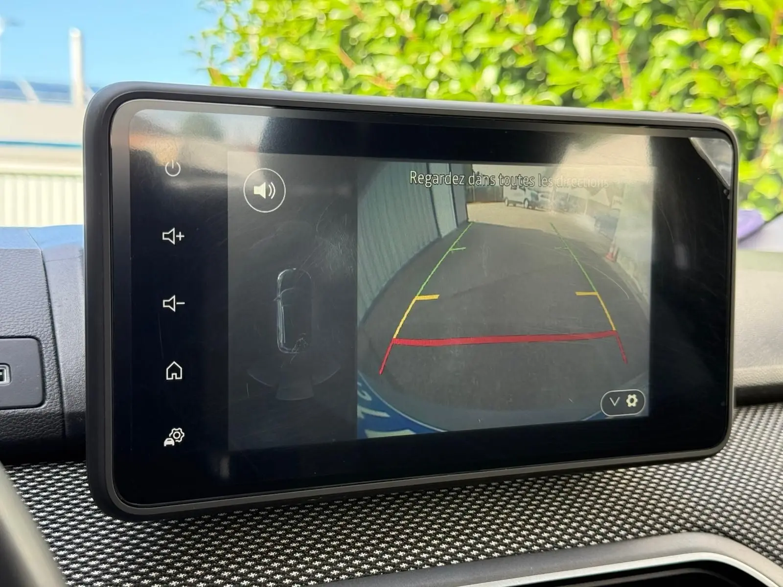 Écran tactile intérieur montrant la caméra de recul du Dacia Sandero blanc version Stepway 2023 avec aides au stationnement.