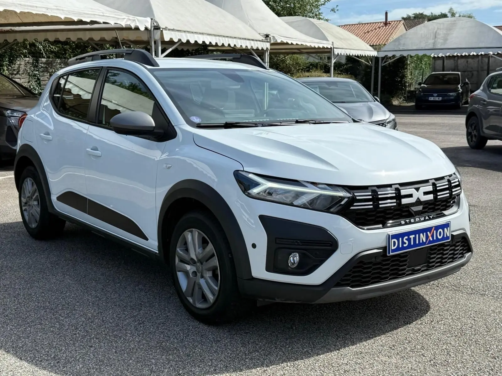 Vue 3/4 avant droite d'une Dacia Sandero Stepway blanche 2023 avec calandre noire et protections latérales noires.