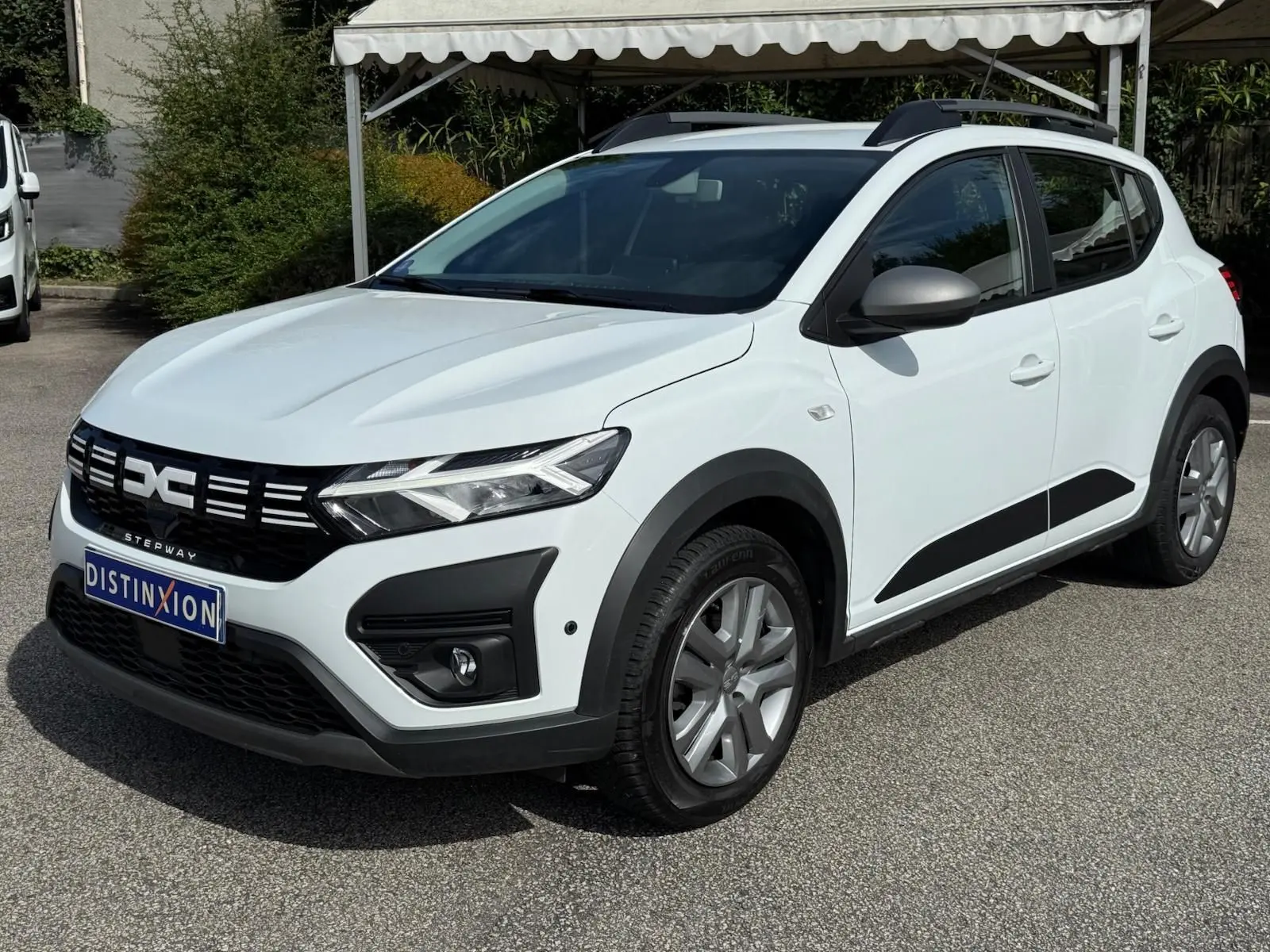 Vue 3/4 avant droite d'une Dacia Sandero Stepway blanche 2023 avec protections noires et jantes alliage.