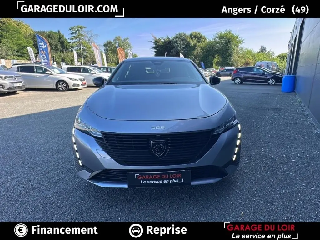 Vue avant frontale d'une Peugeot 308 gris clair avec calandre noire et feux LED verticaux allumés.