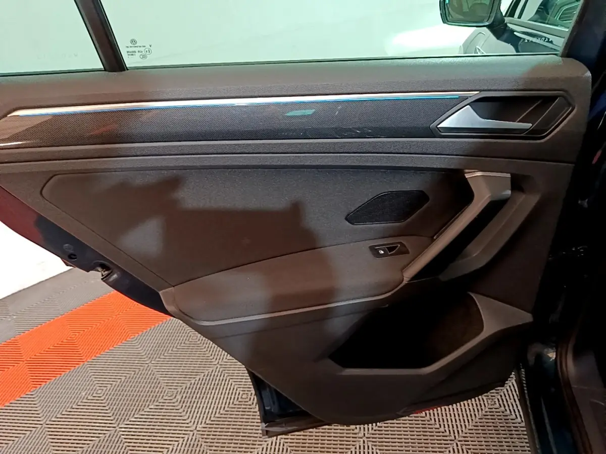 Vue intérieure de la porte arrière droite du Volkswagen Tiguan bleu, avec poignée argentée et haut-parleur intégré.